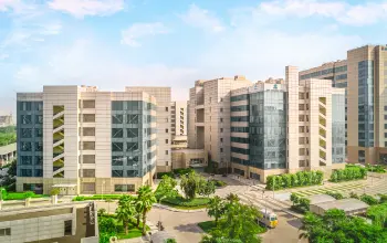 Modern office complex with multiple interconnected buildings, glass facades, and landscaped greenery.