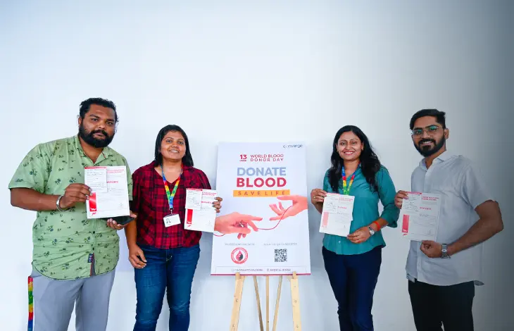 A group of people holding their blood donation certificates in front of a Donate Blood, Save Life poster for World Blood Donor Day