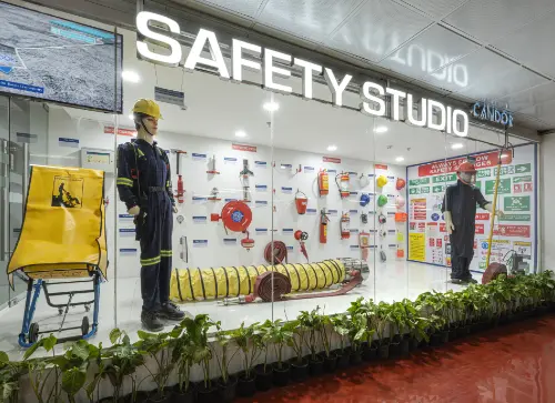 Display of safety equipment in a 'Safety Studio' showcasing gear such as fireman suits, safety signs, and emergency tools, emphasizing workplace safety.