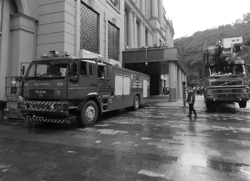 Two fire trucks positioned at the entrance of a building, with a firefighter preparing to assist in an emergency response.