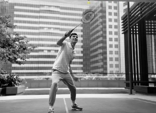 A man playing badminton outdoors at the workplace, enjoying a break amidst the urban surroundings.