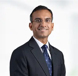 Ankit Gupta, President, is seen smiling in a professional business suit and tie, exuding confidence and leadership in a corporate setting.