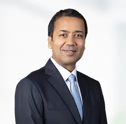 Amit Jain, Chief Financial Officer, smiles confidently in a professional suit and tie, reflecting a strong leadership presence in a corporate setting.