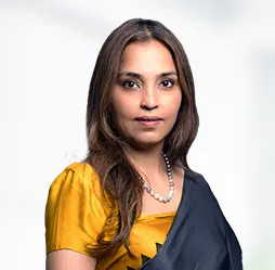 Reema Kundnani, Senior Vice President - Marketing and Key Account Management, poised and confident, dressed in a yellow blouse and a traditional sari, embodying her leadership in marketing and account management.