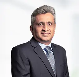 Hetal Joshi, Senior Vice President - Development, in a professional suit and tie, standing confidently as a leader in the development sector.