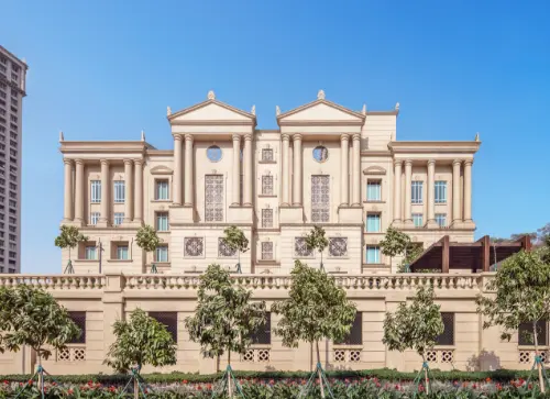 A view of the majestic Fairmont building located in Downtown Powai, Mumbai, showcasing its classical architectural design with grand columns, large windows, and well-maintained landscaping