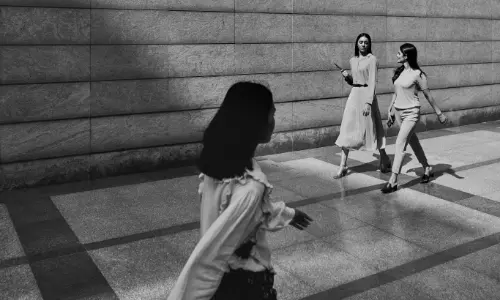Black and white image of three women walking in a modern office corridor at Candor TechSpace, Sector 62, Noida.