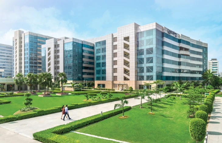 A modern office building at Candor TechSpace, Sector 135, Noida, with greenery and walkways.