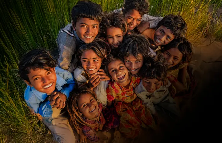 A group of joyful children smiling and embracing one another in a field.