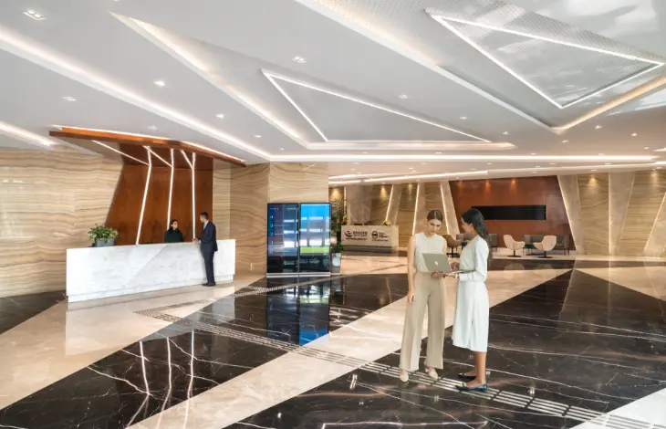 Two women standing and discussing in the lobby of Candor TechSpace, Sector 48, Gurugram, with a reception desk in the background