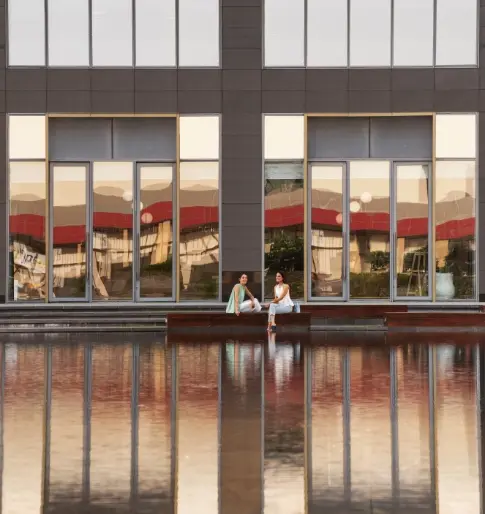 Candor TechSpace, Sector 135, Noida, featuring a modern office building with large glass windows and a reflective water body.