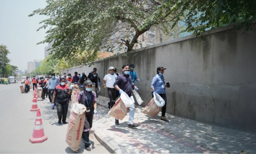 A group of people participating in a community cleanup initiative, carrying large sacks for waste collection as they walk along the street, promoting environmental responsibility