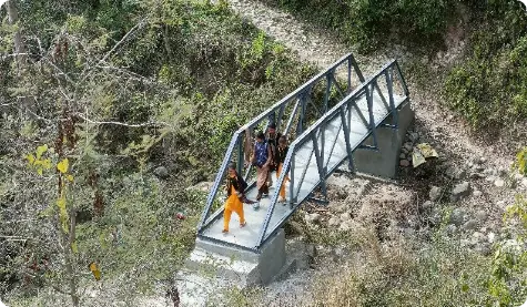 A group of locals crossing a newly constructed footbridge in a village in Raesi District, Jammu. The bridge, built through the efforts of the ICICI Foundation, spans a rocky terrain, providing a safe passage for villagers and showcasing the foundation's commitment to infrastructure development in rural areas.