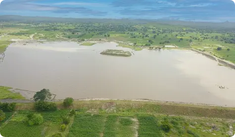 Aerial view of Alkoda Lake in Raichur District, Karnataka, showing the successful rejuvenation efforts by ICICI Bank. The lake is surrounded by lush green fields and stretches across a large area, demonstrating the positive environmental impact of the initiative.