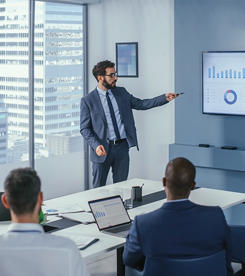 A person in a suit pointing at a screen