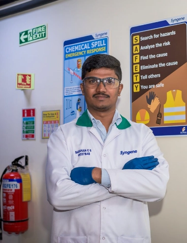 A person wearing a white lab coat and blue gloves